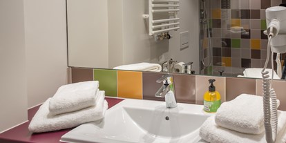 Wanderurlaub - Hotel-Schwerpunkt: Wandern am See - Das farbenfrohe Badezimmer mit geräumiger Dusche - Explorer Hotel Ötztal